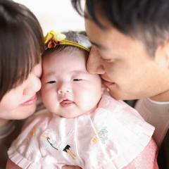両親にキスをされる赤ちゃん
