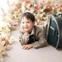 緑色のランドセルの横で嬉しそうな男の子